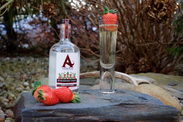 a bottle of strawberry vodka with a champagne cocktail and ripe strawberries