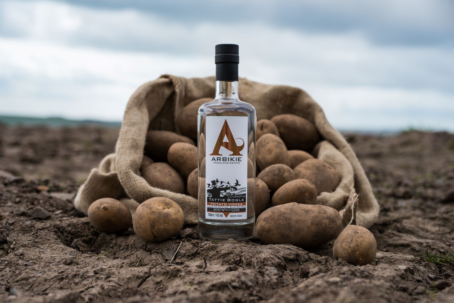 a bottle of vodka in a field with potatoes