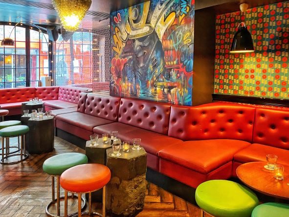 an eclectic bar with a riot of colour with low slung chairs and tables