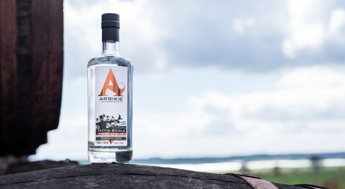A bottle of tattie bogle vodka on a wooden barrel