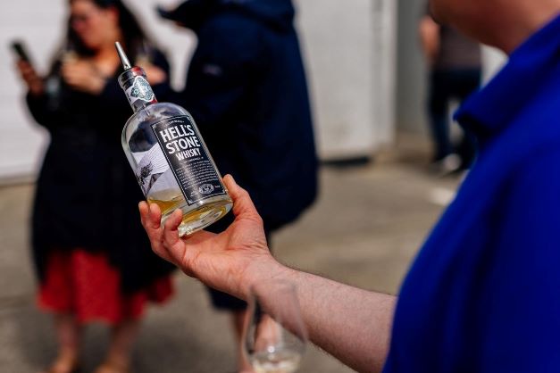 a bottle of hell's stone whisky being held by a man