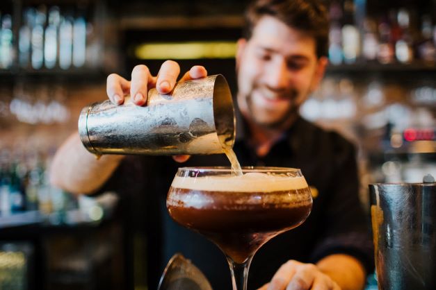barman making a cocktail, pouring from a shaker
