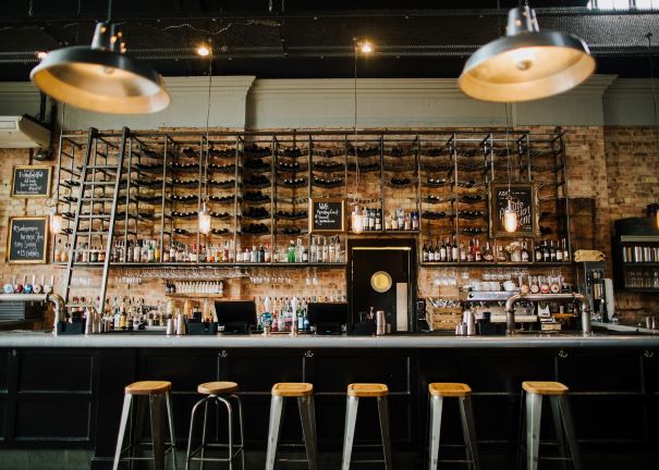 a fully stocked backbar with industrial furnishings and low stools at the bar