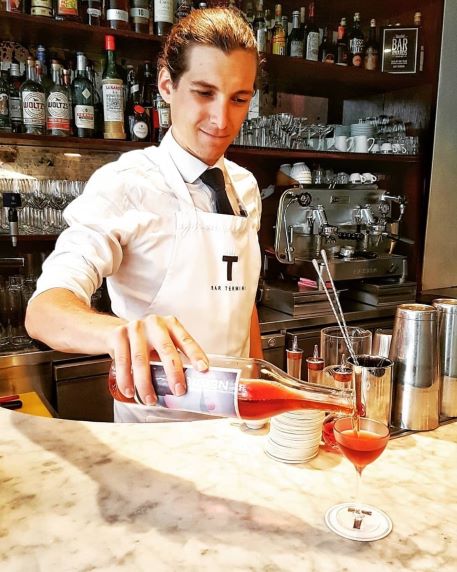 a man serving negroni from a bottle in an italian bar