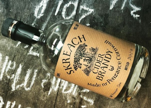 a bottle of skreach cider brandy on a wooden table with chalk writing