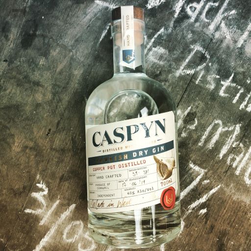 a bottle of caspyn gin on a wooden table that has been drawn on with chalk