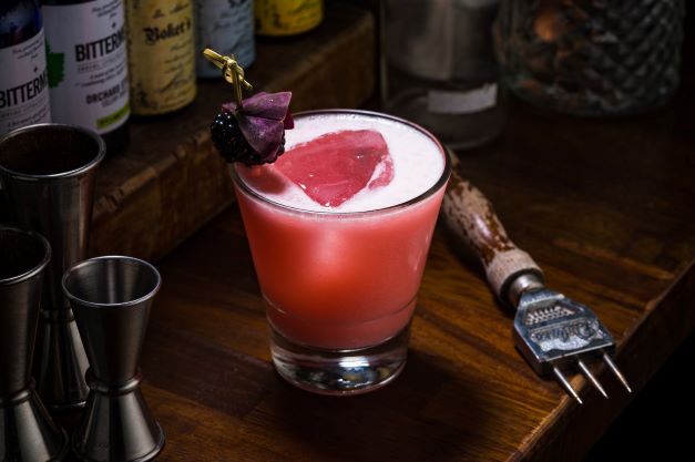 a cocktail with ice pick and jiggers behind a bar