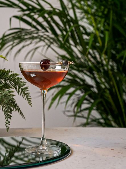 Manhattan cocktail in a coupe glass garnished with a cherry