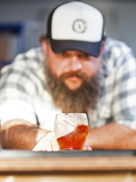 Man looking at red drink in glass with ice