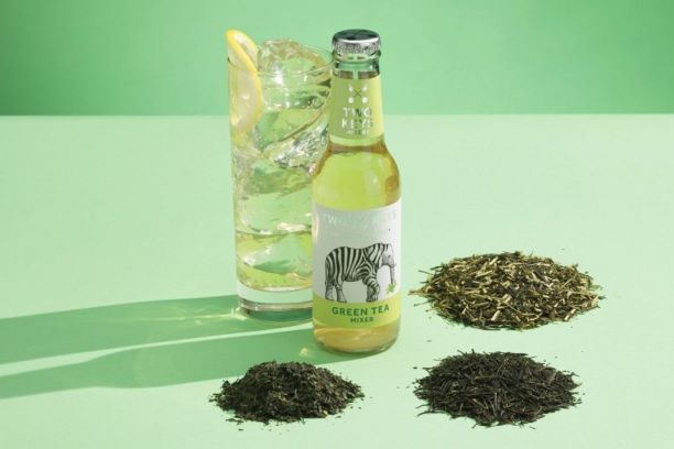 a bottle of two keys green tea mixer with a cocktail and green background