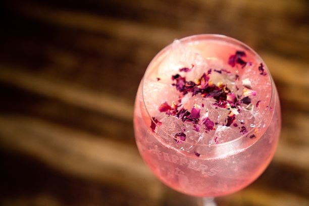a pink gin and tonic on a wooden counter